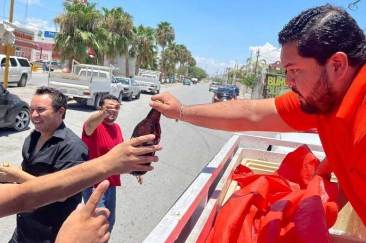 Jóven de Búfalos Torreón entregando una caguama a hombre sonriente.