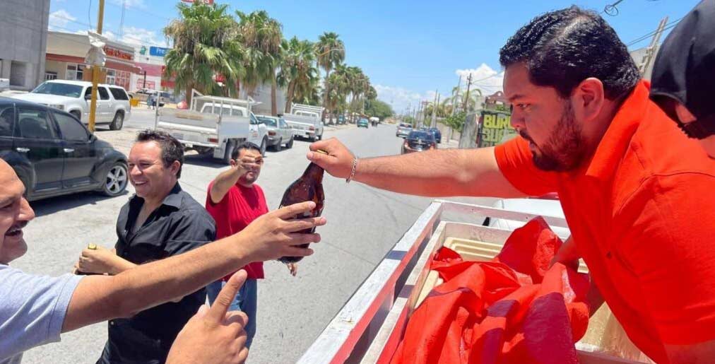 Jóven de Búfalos Torreón entregando una caguama a hombre sonriente.